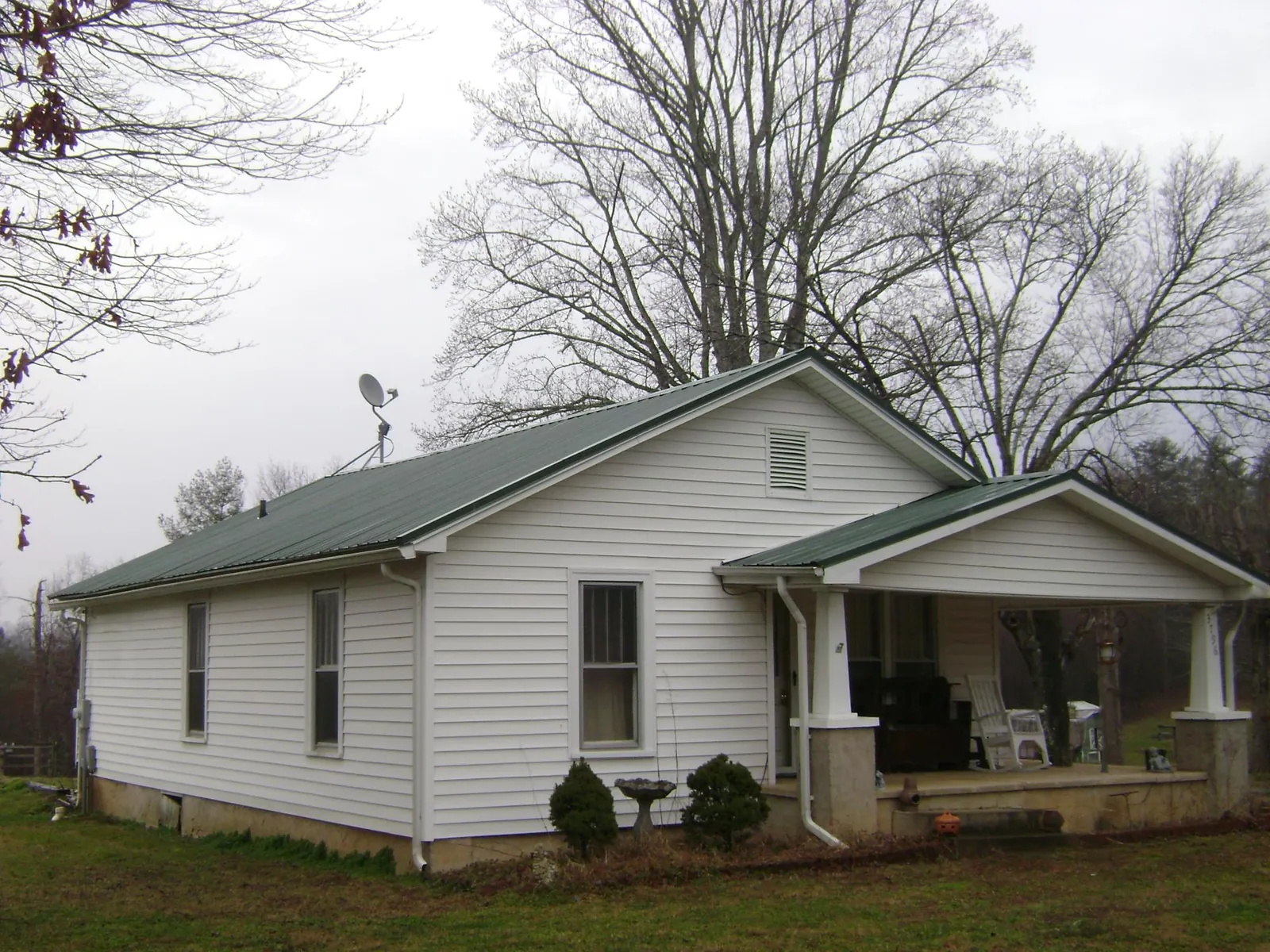 Green metal roof on a white bungalow with a side porch in Lewiston