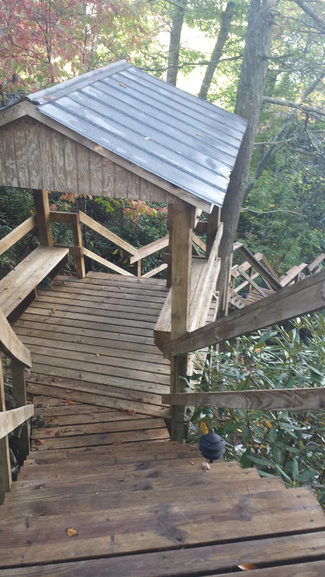 Metal roofed shelter over wooden steps on a wooded walkway — Skylight Repair & Installation work by our crew in Lewiston